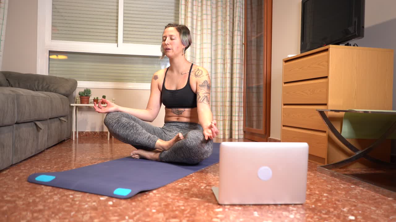 la mujer realiza la respiración de yoga y saluda a su clase en línea usando la computadora