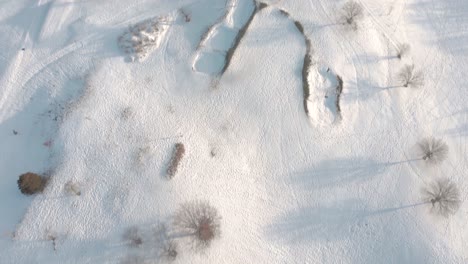 El-Dron-Retrocede-Y-Gira-Hacia-Abajo-Para-Mostrar-El-Club-De-Campo-Cubierto-De-Nieve,-Los-Tees-Y-Otras-Características-Del-Campo-De-Golf-Posterior-A-La-Tormenta-De-Nieve