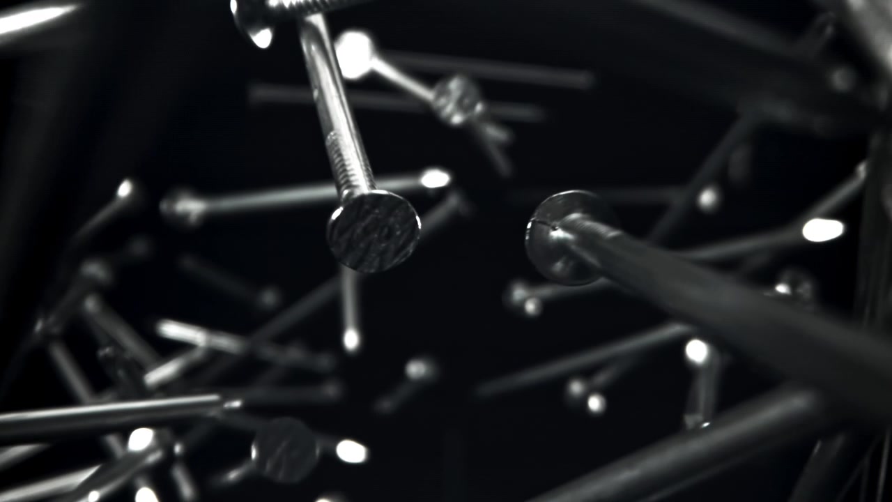 Movimento lento astratto di chiodi e viti di metallo che fluttuano sul nero