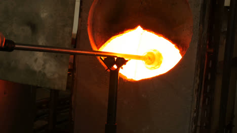 glassblower heating a glass in furnace