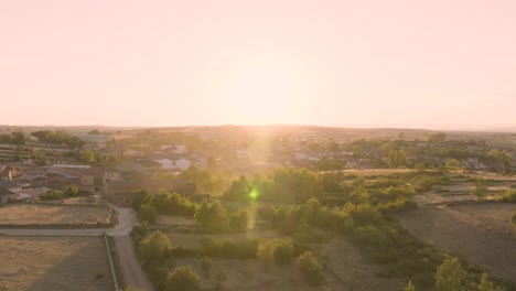 aerial of residential homes in rural valley hills with sun flare at sunset