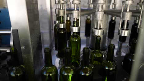 wine green glass bottles filling up with red wine at an automated production line in vignonet france, pan left medium shot