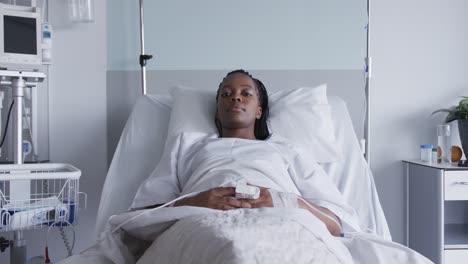 african american female patient lying in bed in hospital room, slow motion