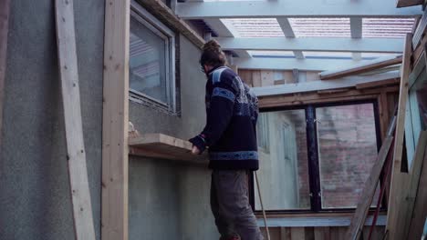 Hombre-Colocando-Un-Tablón-De-Madera-En-La-Pared-Interior-Del-Invernadero