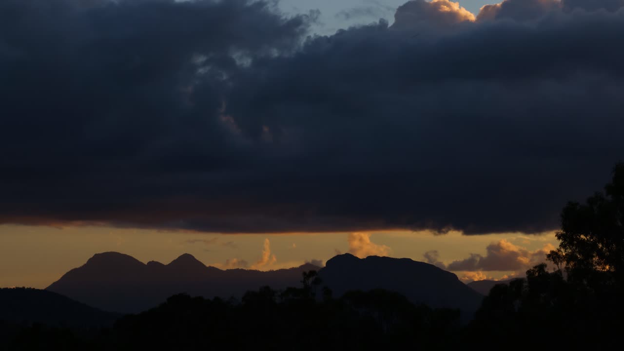 구름과 산 뒤에 있는 해가 지는 시간대