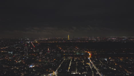 from above, the city's lights dance, and the eiffel tower casts its glow over th