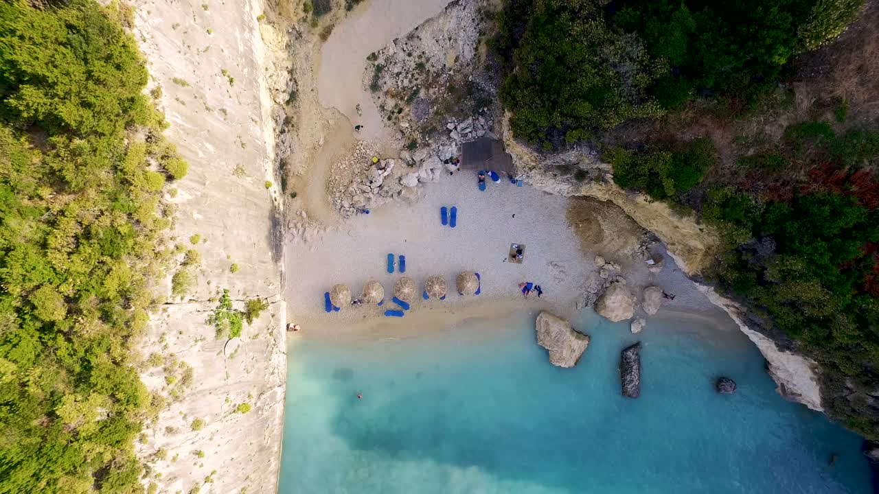Retreating overhead drone shot, pulling away from the secluded beachfront of Xigia, showing the rock-sheltered cove and the sulphureous waters in Zankynthos Island in Greece