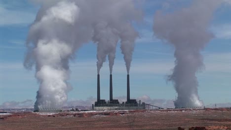 mediumshot of a factory in the arizona desert belching polluting fumes into the air