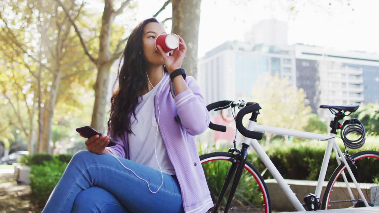 mujer asiática con auriculares escuchando música y bebiendo café para llevar