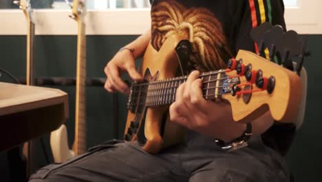 Handheld-shot-of-man-playing-bass-guitar-with-groove-in-recording-studio