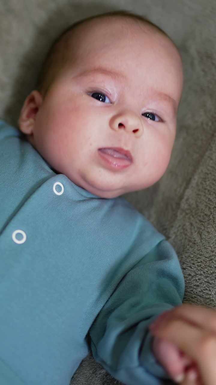 Baby laying on the back. Small cute kid lyiing on the bed. Vertical video