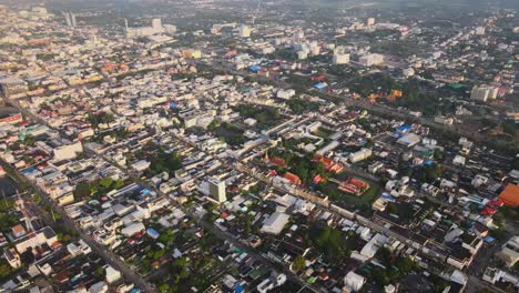 aerial: drone panning down high above a buddhist temple surrounded by densely populated nakhon ratchasima town in korat province, thailand