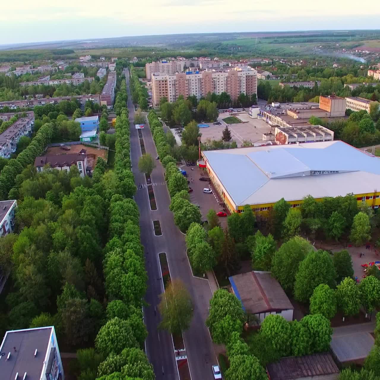Good plain road going through the green residential area. Ukrainian city scenic panorama at the backdrop of blue sky