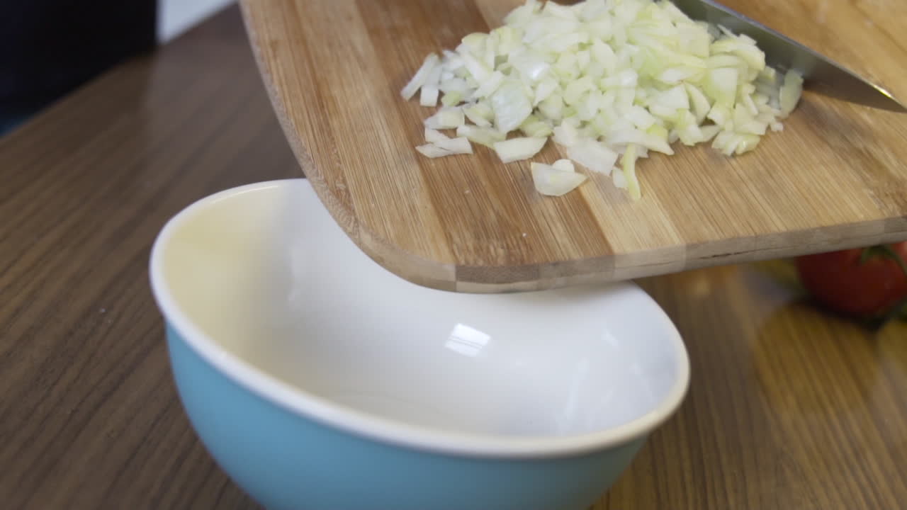 Putting, pushing onions in a bowl from the chopping board, preparing food, vegan diet to loose weight slow motion