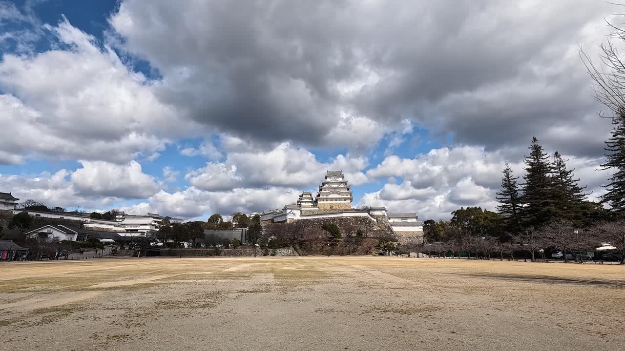 Scenic Wide View of Himeji Castle in Hyogo Japan under Cloudy Blue Sky with Open Field in Foreground. Himeji Castle in Hyogo Japan