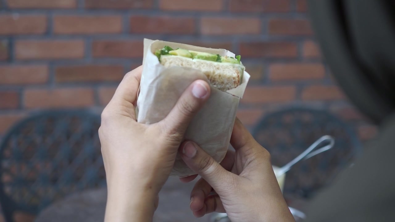 Person holder en frisk avocadomad i papirindpakning