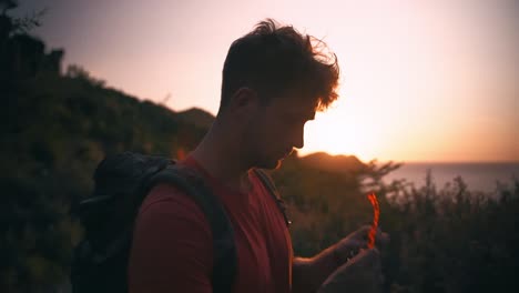 Closeup-view-of-a-silhouette-young-man-wearing-sunglasses-and-trekking-during-sunset