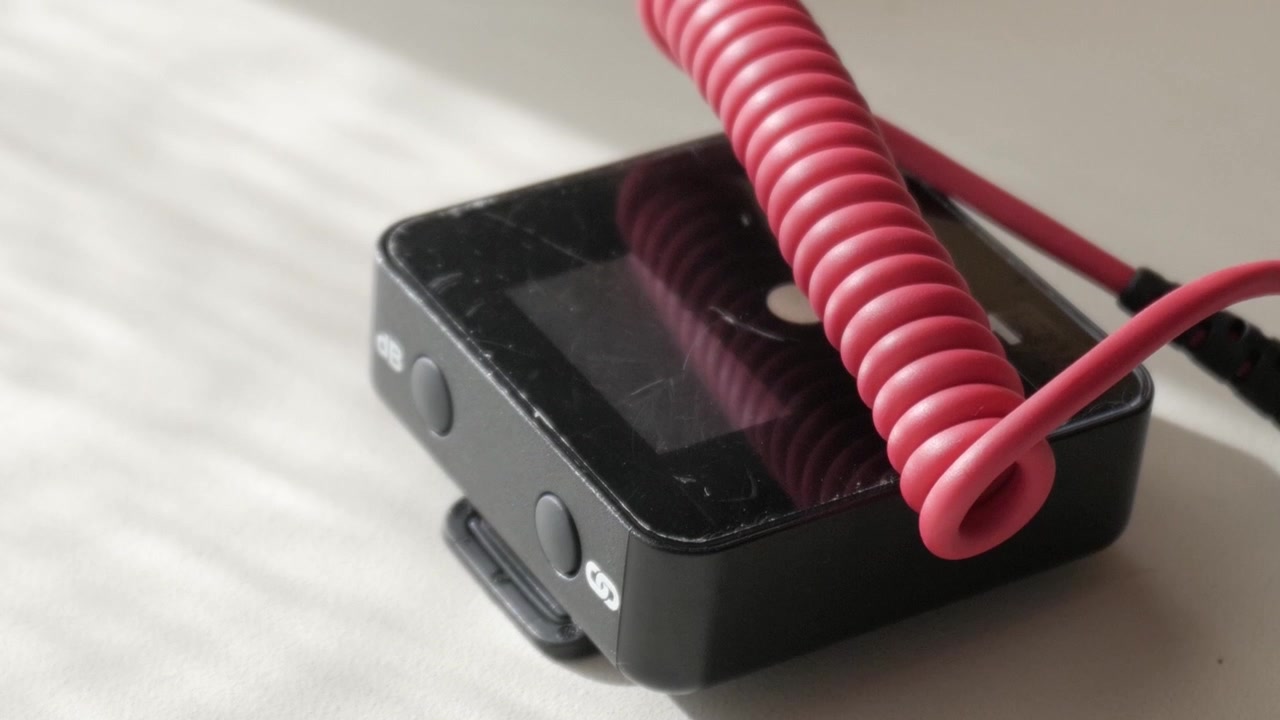Primo piano di un microfono lavalier wireless su un tavolo con cavo a spirale.