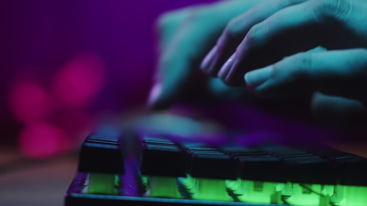 Nærbillede af hænder, der taster på et neonoplyst gaming-tastatur