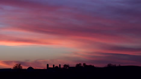 Una-Hermosa-Atardecer-Sobre-El-Medio-Oeste-De-Estados-Unidos-Con-Granjas-Y-Graneros-En-La-Distancia