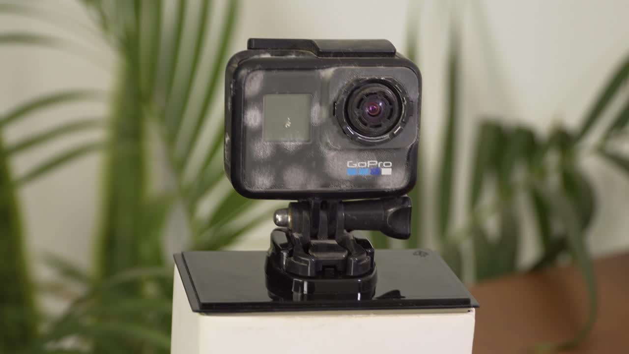 손상된 고프로 카메라, 삼각대 마운트에 부착, 세밀하게 세부 사항으로 포착, 왼쪽에서 오른쪽으로 천천히 이동