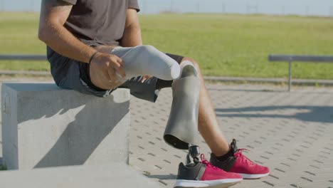 medium closeup shot of male athlete putting on prosthetic leg.