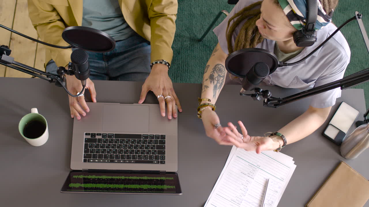 vista superior de manos de hombre y manos de mujer gesticulando sobre la mesa mientras graban un podcast