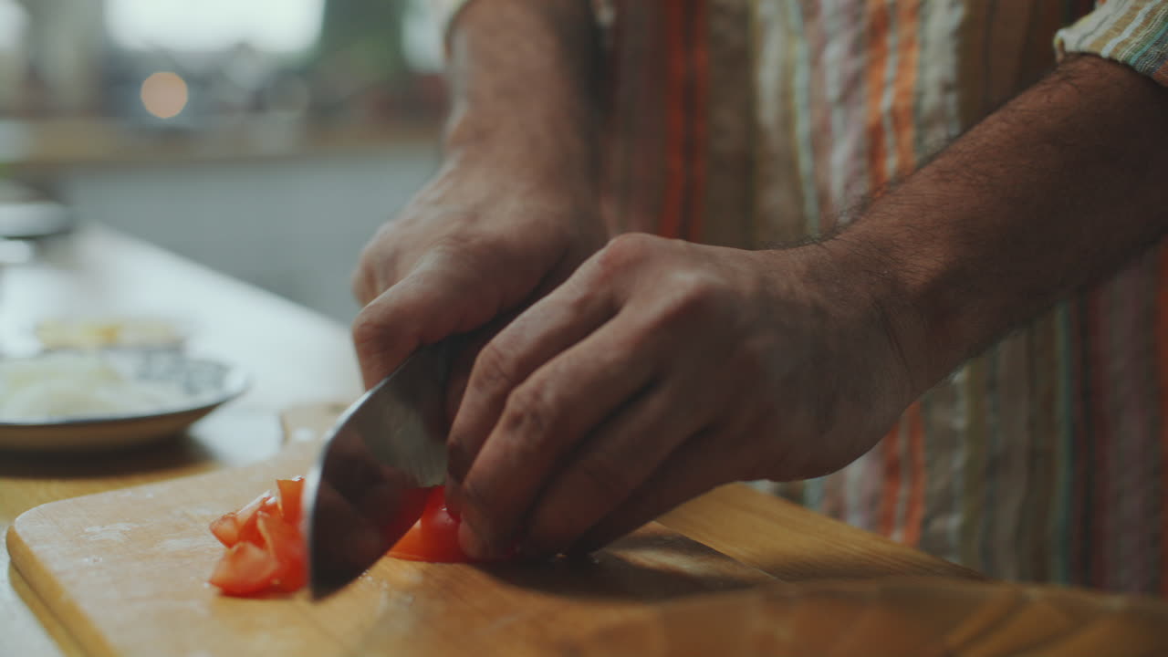 primer plano de las manos del chef cortando tomate fresco en la encimera de la cocina