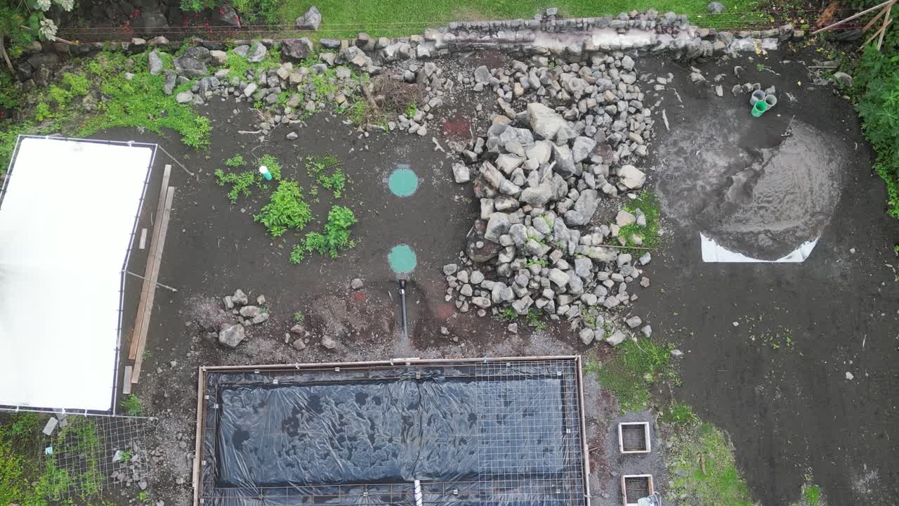 Drone flying over rectangular house foundations on Big Island, Hawaii, from bottom to top in a top-down view.