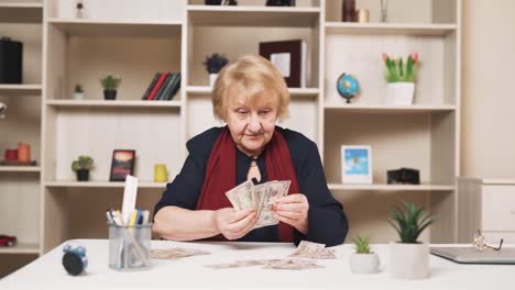 elderly woman happily counts dollar bills, arranging them on the table