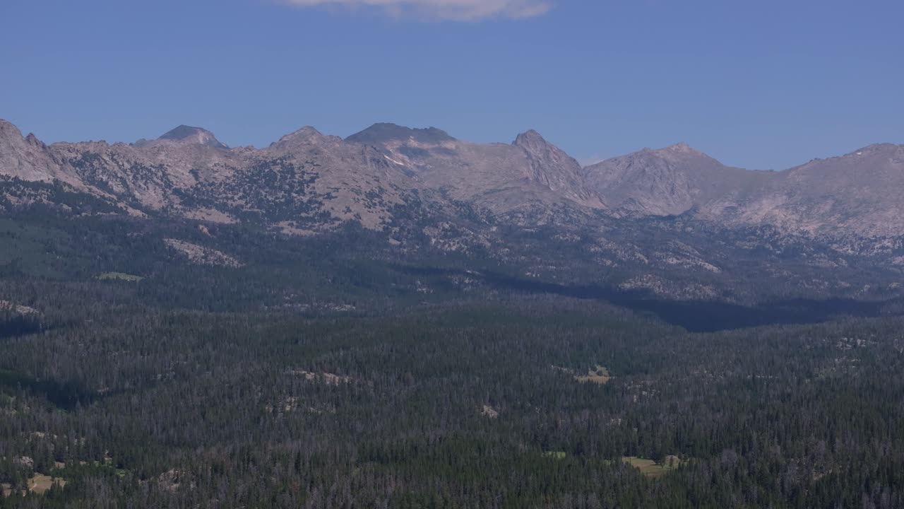Drone establishing view of Wind River Wilderness in Wyoming, showcasing dense forests, mountain peaks, and wide open plains near the Big Sandy Trailhead
