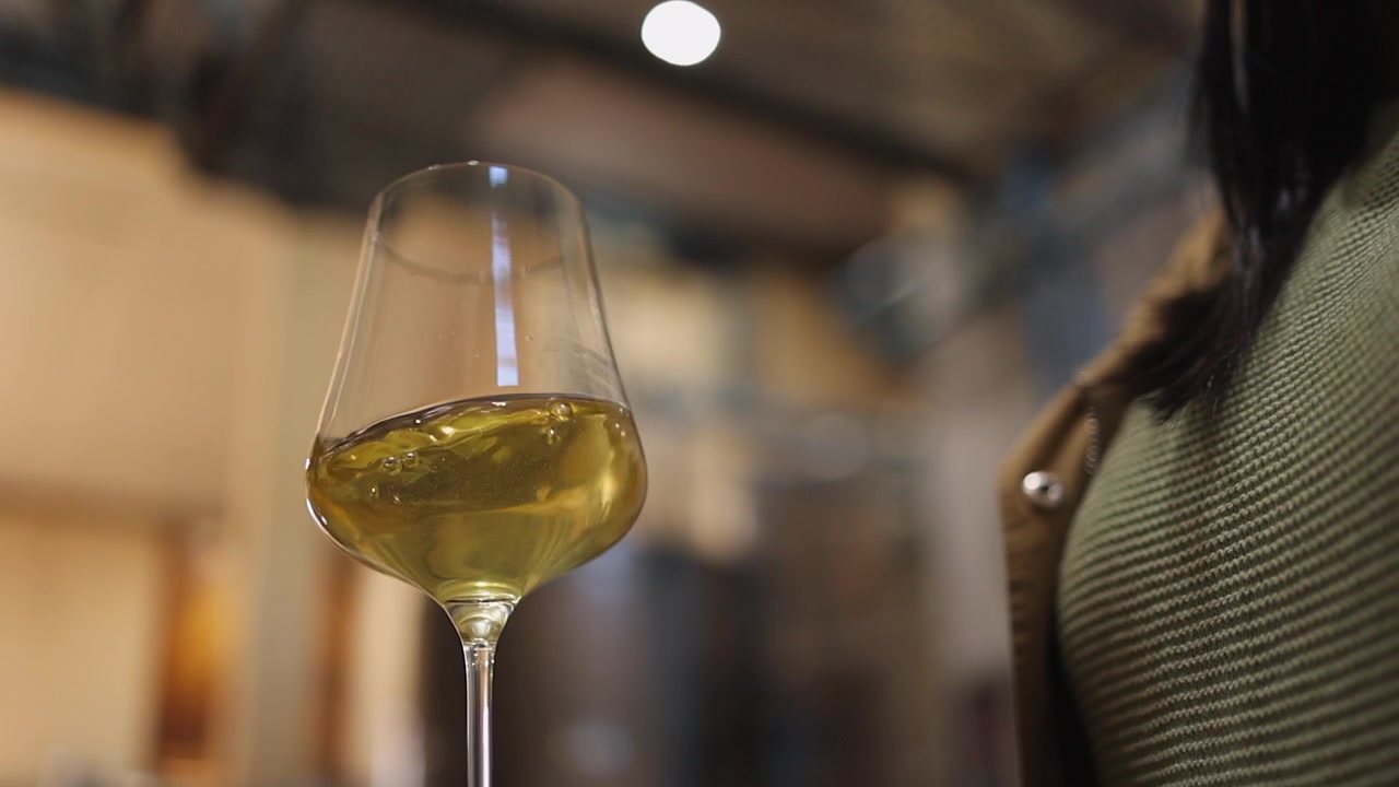 Angolazione bassa: il vino bianco viene fatto roteare in un bicchiere da vino angolare per aerarlo.