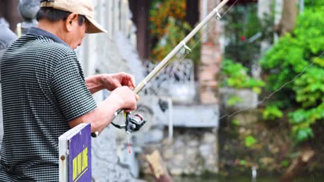 man fishing near lush greenery and architecture