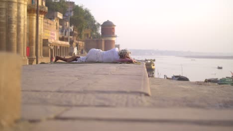 elderly woman lying on a wall by the ganges