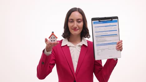 a woman holding an insurance form and a model house