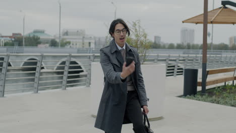 businessman reacting to something on his phone in an urban park