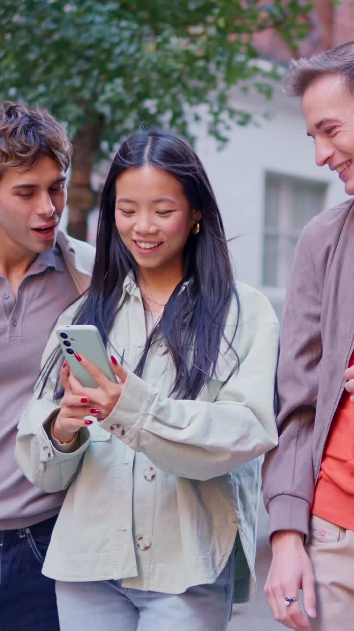 Teman Muda Tertawa dan Berbagi Konten di Smartphone di Luar Ruangan