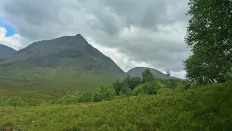clouds over meadow, fields, and mountains in highlands of scotland. - pan shot