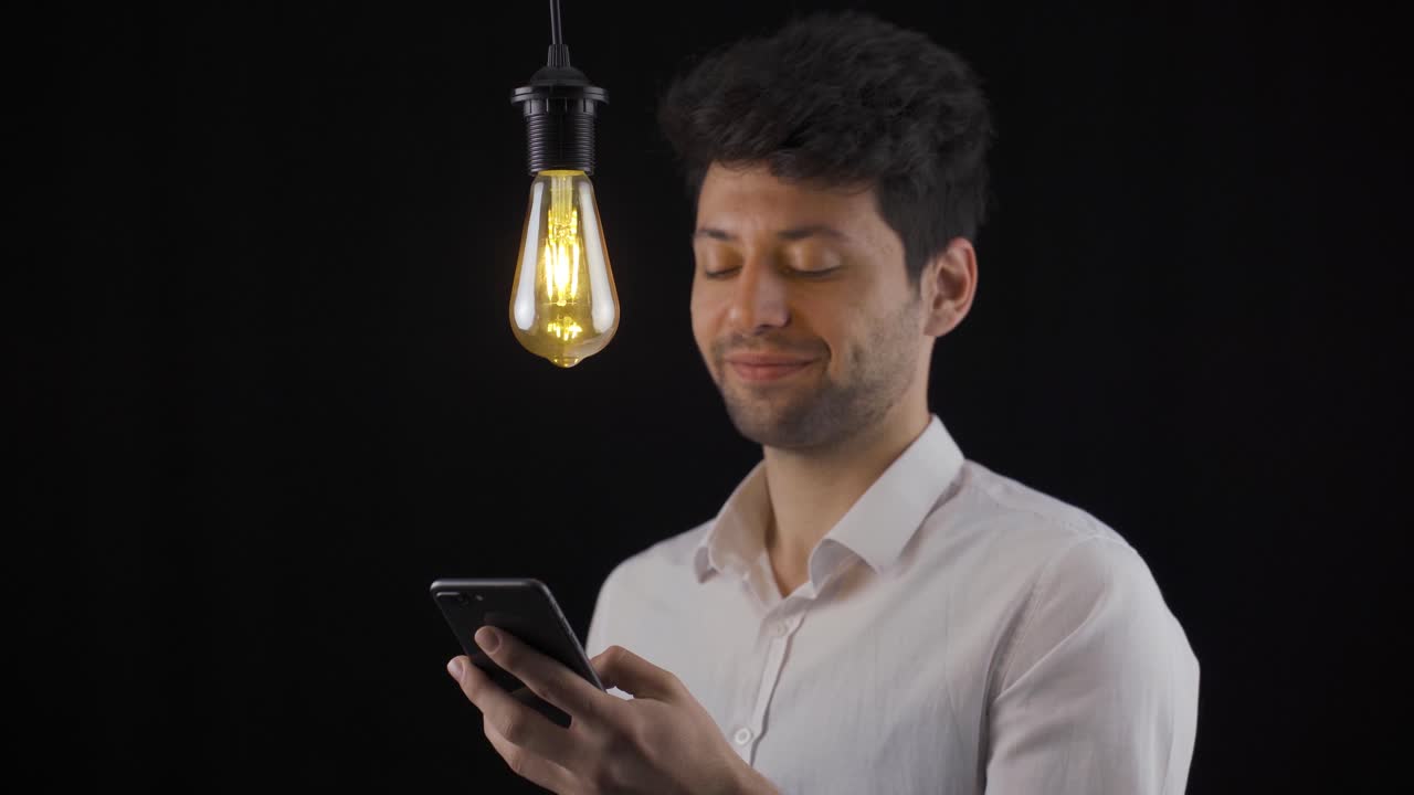 el hombre que mira el teléfono tiene una nueva idea y la lámpara se enciende. eureka