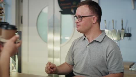 Caucasian-man-with-down-syndrome-giving-take-away-food-to-a-female-client.