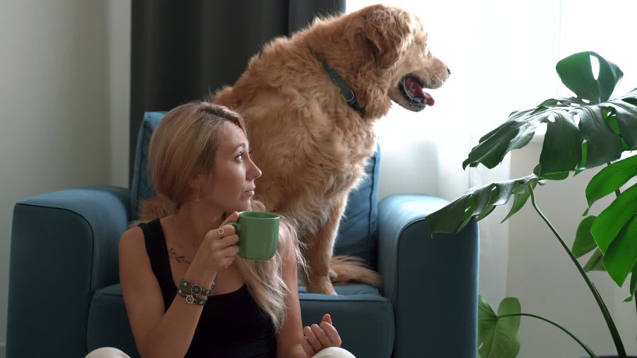 골든 리트리버 개와 함께 커피를 마시는 여자.