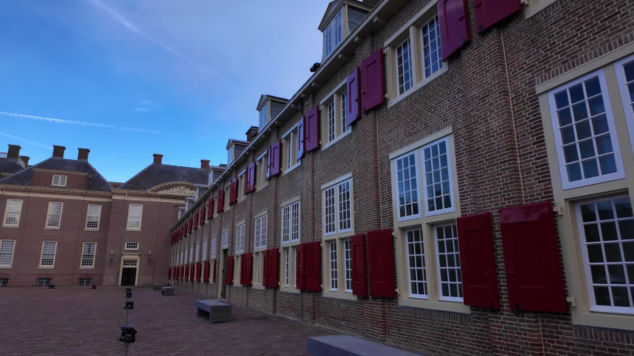 Udvendig murstensfacade af Paleis Het Loo med traditionelle røde skodder på vinduerne. Historisk hollandsk barokarkitektur under blå himmel i vinterferieperioden i Apeldoorn.