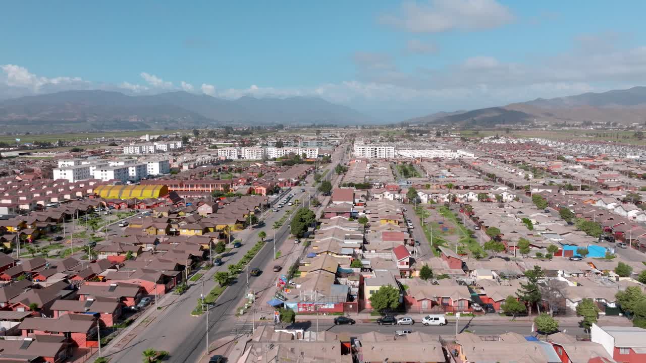 vista aérea panorámica de casas similares con edificios bajos y montañas áridas con nubes en el fondo, la serena, chile