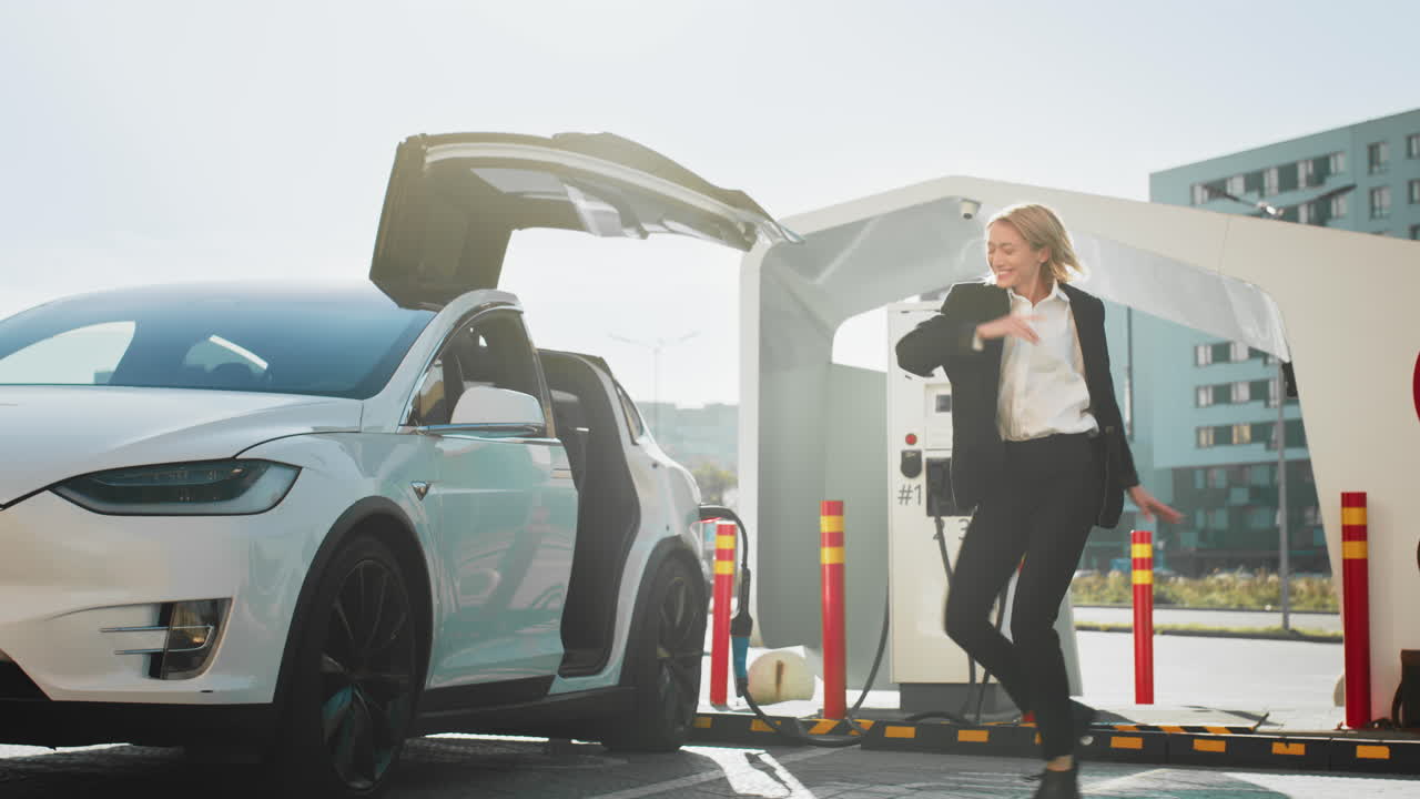 충전소 에서 전기 자동차 를 충전 하는 여자