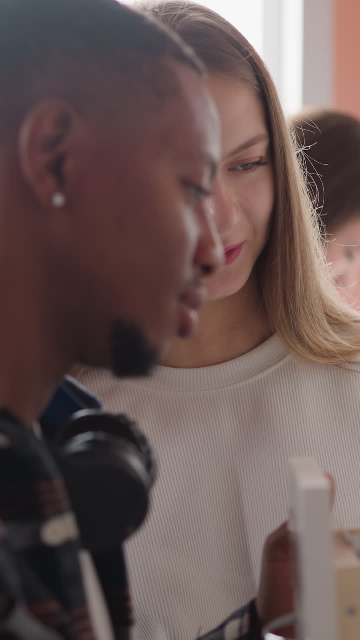 Blonde librarian helps man to find data in card index. Woman teaches black guy to work with archive information in drawer unit. People seek records