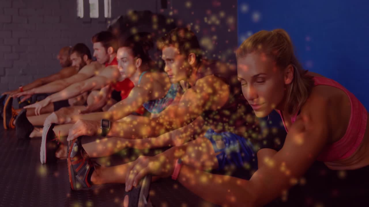 Gym classmates upon reaching forward in seated stretch generating golden sparkles for fitness focus