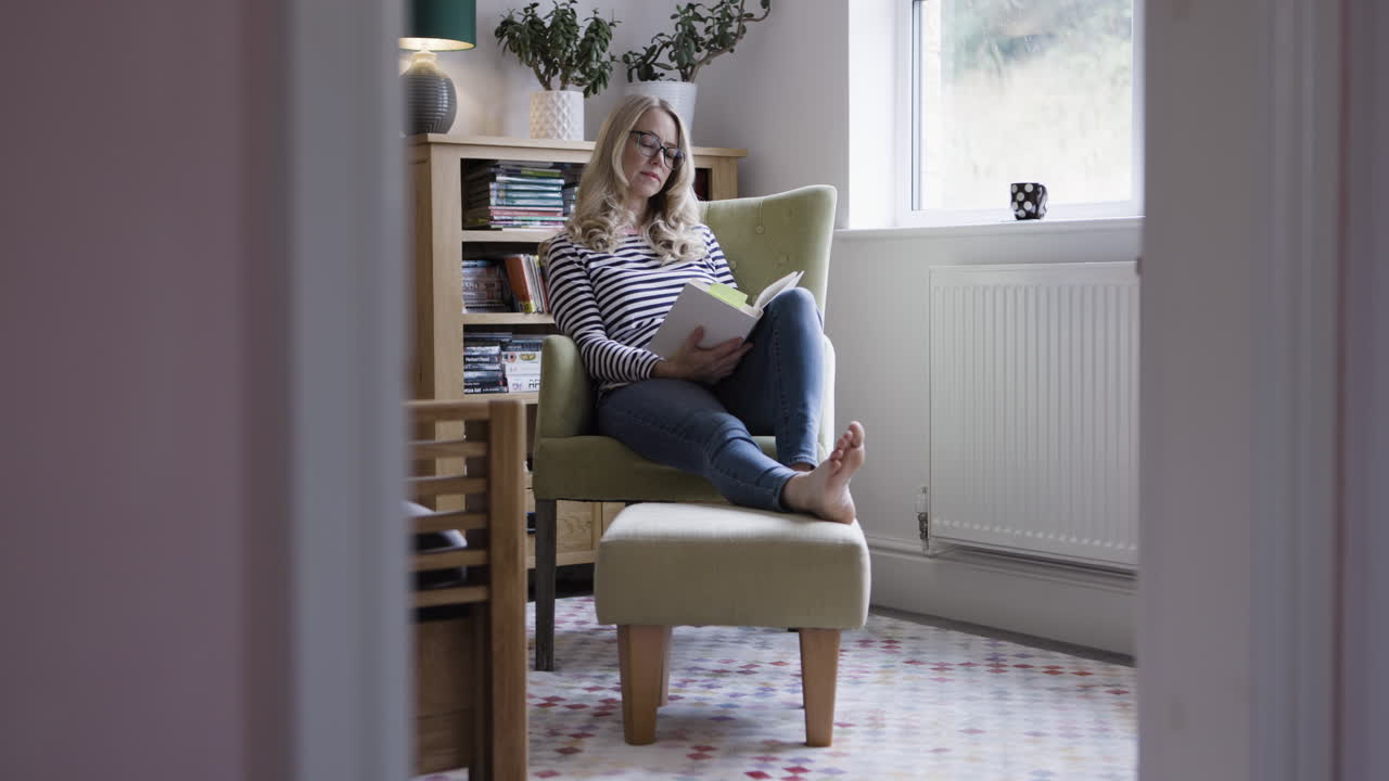 Woman reading a book in a comfortable chair at home