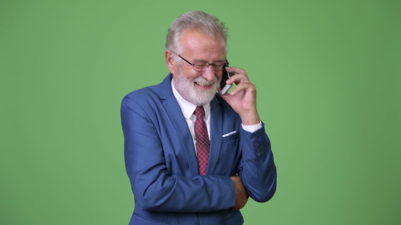 Handsome senior bearded businessman against green background