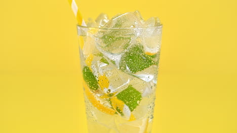 glass of lemonade with lemons and mint splashed with water on the black background in slow motion