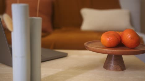 oranges on wooden stand with tall vases and laptop